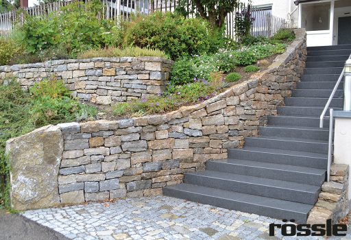 Vorgarten mit Basalt Blockstufen und einer Muschelkalk-Mauer inklusive Findling